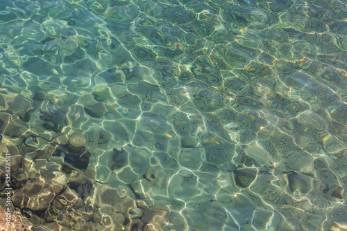 Overview of the seabed seen from above, transparent water of the Red sea in Eilat, Israel. Seabed Background. View from above to a stony seabed in clear water with abstract blue green pattern. Diving