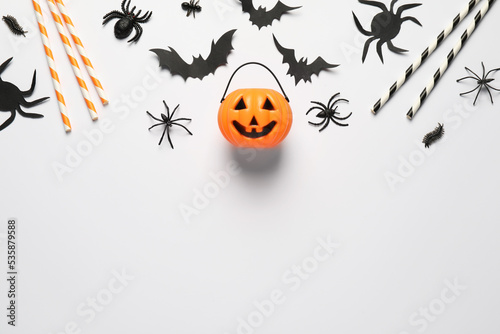 Flat lay composition with plastic pumpkin basket and paper bats on white background, space for text. Halloween celebration