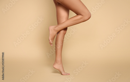 Quadro su tela Woman with beautiful long legs on beige background, closeup