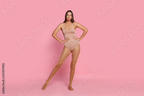 Beautiful woman wearing tights and bodysuit on pink background