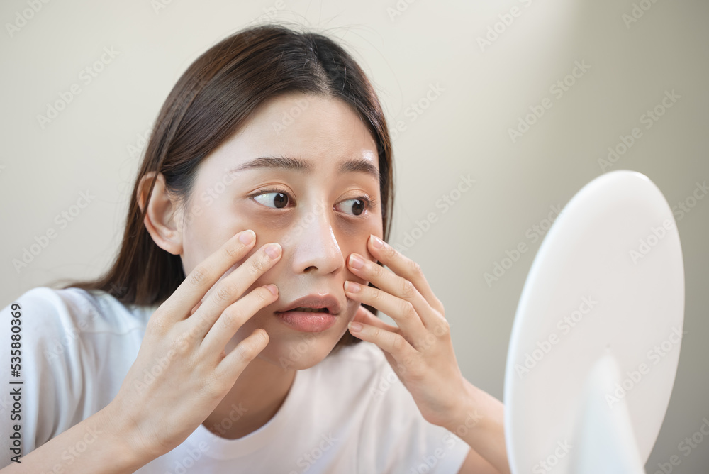 Sleepless Asian woman looking her face in the mirror and worry about dark circles under eyes Sleepless Asian woman looking her face in the mirror and worry about dark circles under eyes