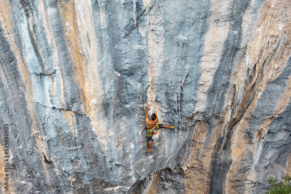 Extreme sport, strong man, rock climber climbs a difficult route.