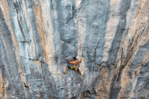 Extreme sport, strong man, rock climber climbs a difficult route.