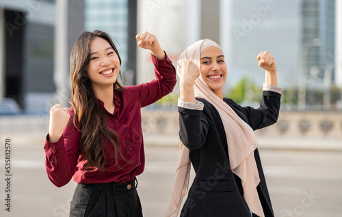 multiracial empowered businesswomen, show their bicep muscle. in the city.