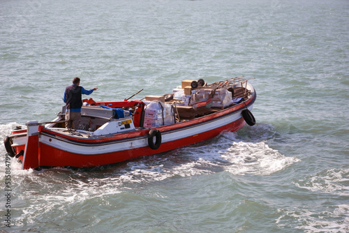 A motorized transport boat transports cargo on sea foam waves © Serhii