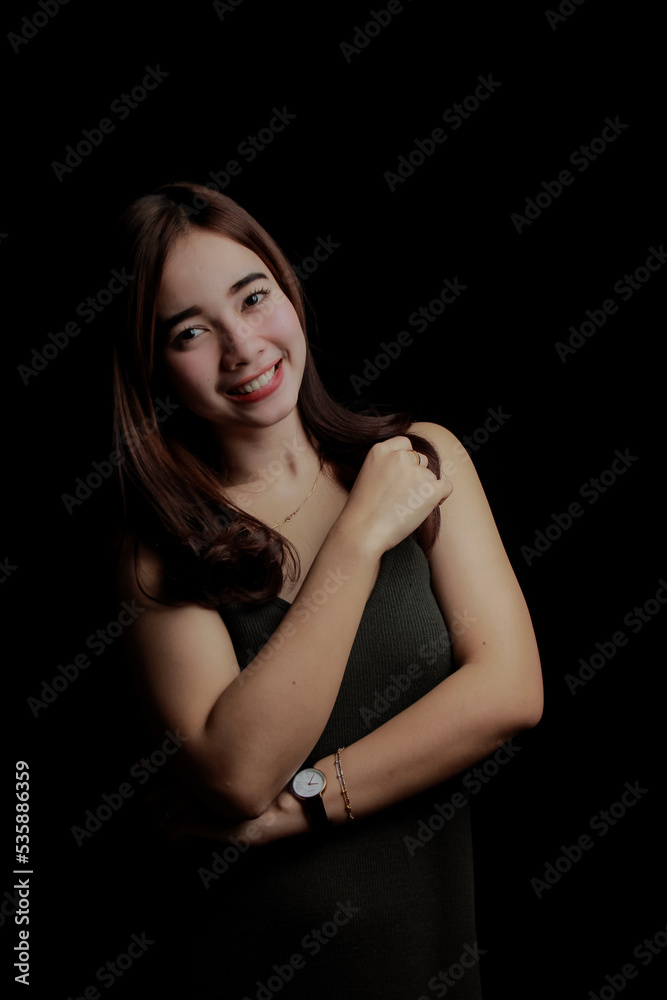 young Asian women wear dresses or dark clothes. Take pictures and express themselves inside the indoor studio. On a dark black background.