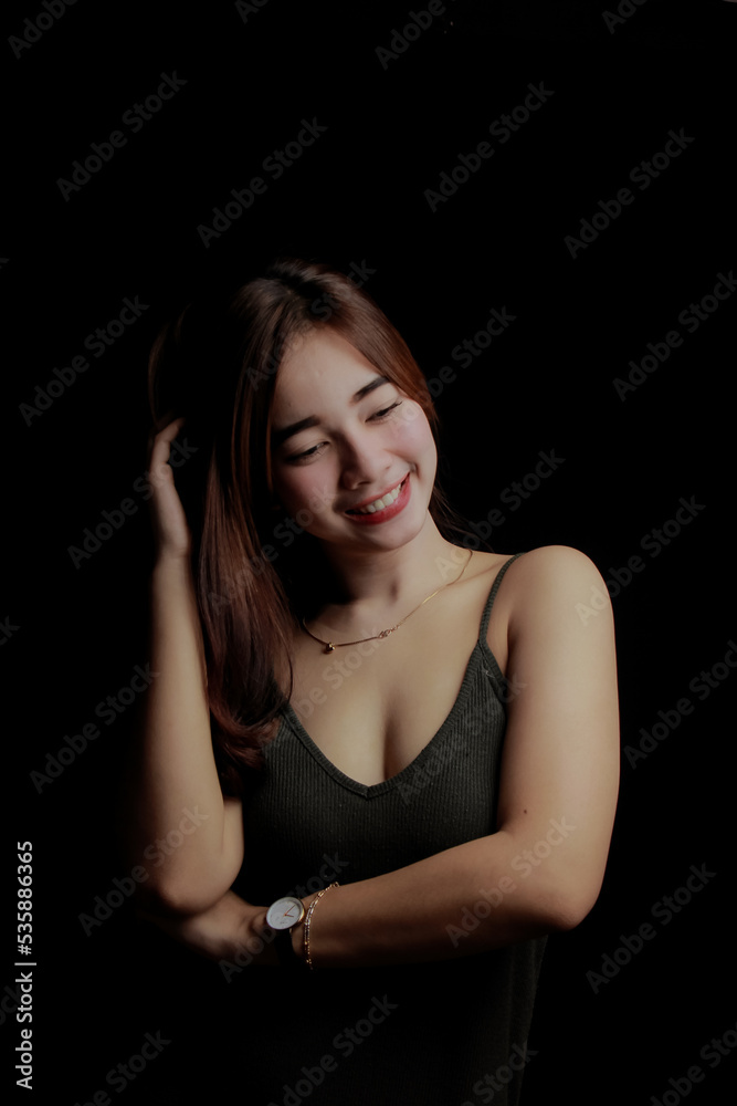 young Asian women wear dresses or dark clothes. Take pictures and express themselves inside the indoor studio. On a dark black background.