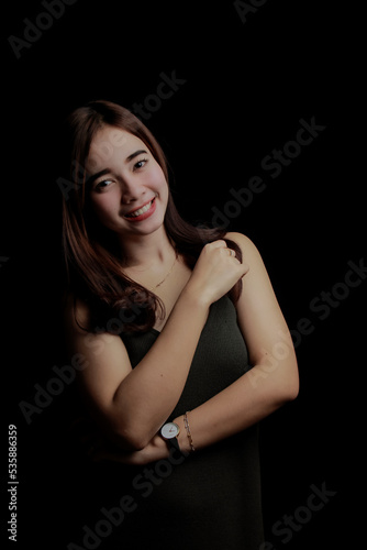 young Asian women wear dresses or dark clothes. Take pictures and express themselves inside the indoor studio. On a dark black background.