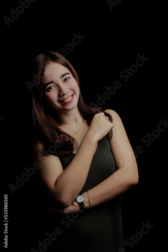 young Asian women wear dresses or dark clothes. Take pictures and express themselves inside the indoor studio. On a dark black background.