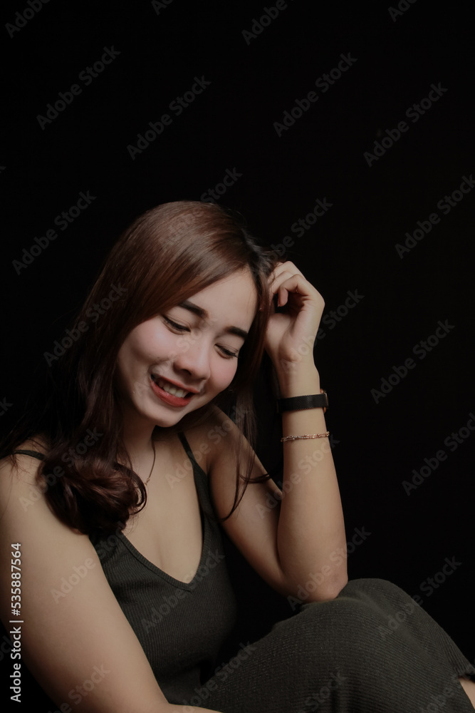young Asian women wear dresses or dark clothes. Take pictures and express themselves inside the indoor studio. On a dark black background. young Asian women wear dresses or dark clothes. Take pictures and express themselves inside the indoor studio. On a dark black background.