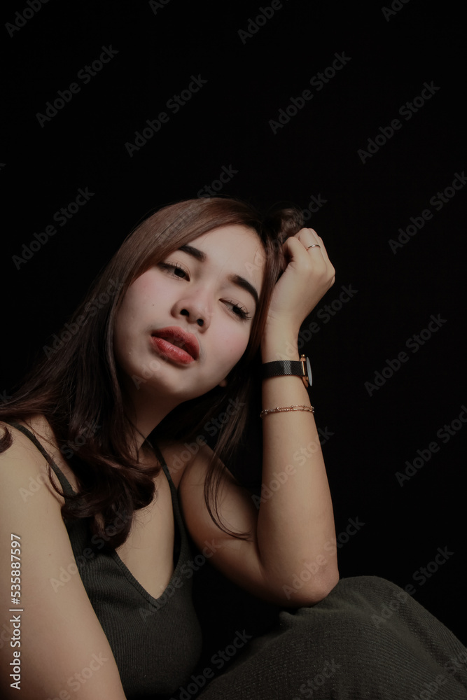 young Asian women wear dresses or dark clothes. Take pictures and express themselves inside the indoor studio. On a dark black background. young Asian women wear dresses or dark clothes. Take pictures and express themselves inside the indoor studio. On a dark black background.