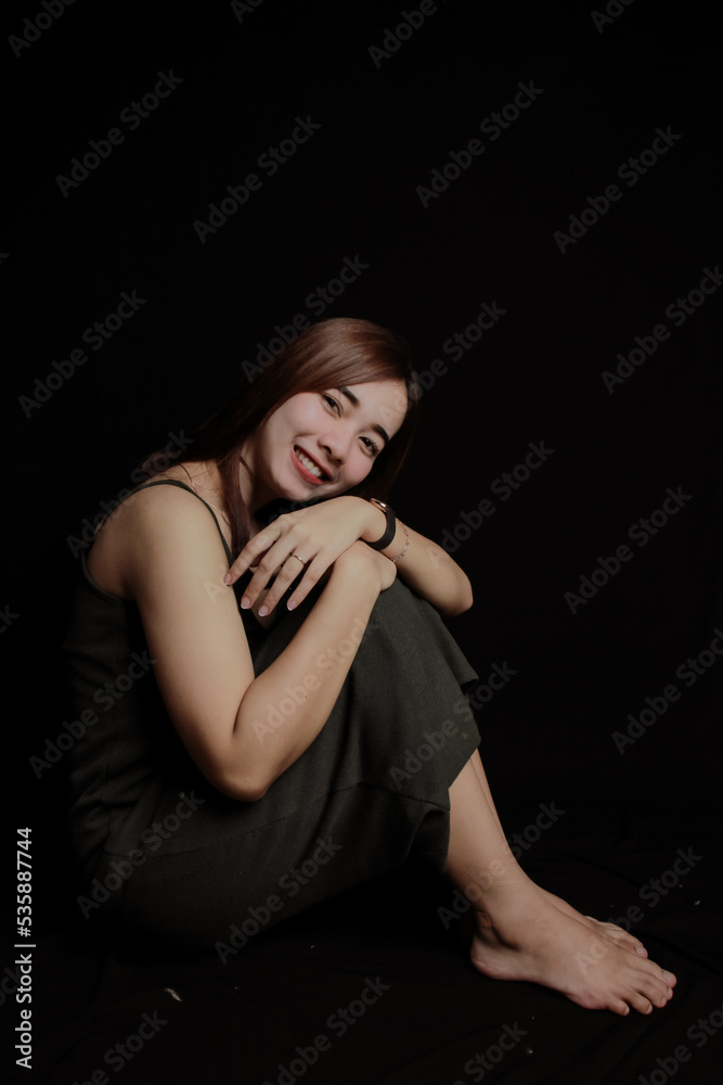 young Asian women wear dresses or dark clothes. Take pictures and express themselves inside the indoor studio. On a dark black background. young Asian women wear dresses or dark clothes. Take pictures and express themselves inside the indoor studio. On a dark black background.
