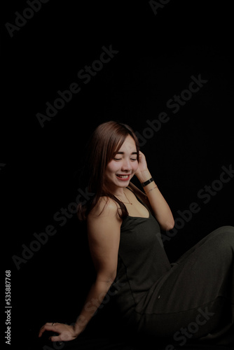 young Asian women wear dresses or dark clothes. Take pictures and express themselves inside the indoor studio. On a dark black background.