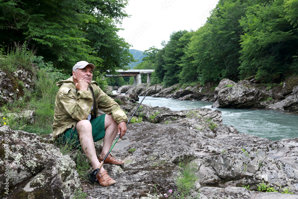Senior man on bank of Belaya river in granite gorge