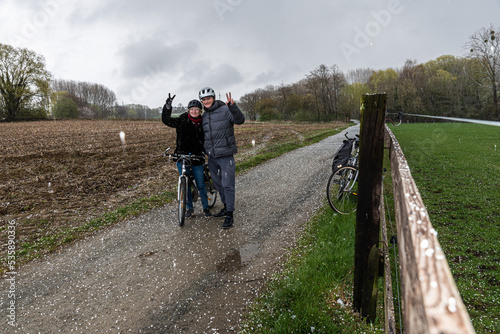 Bicycle couple posing in the hail with their bikes in the nature fields photo