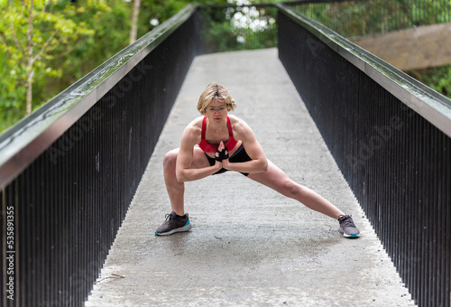 Strong thirty year old woman stretching outdoors photo