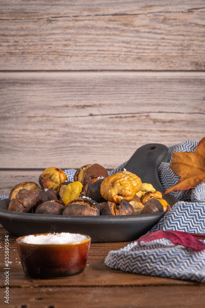 Fototapeta premium Roasted chestnuts in cast iron pan on an old board