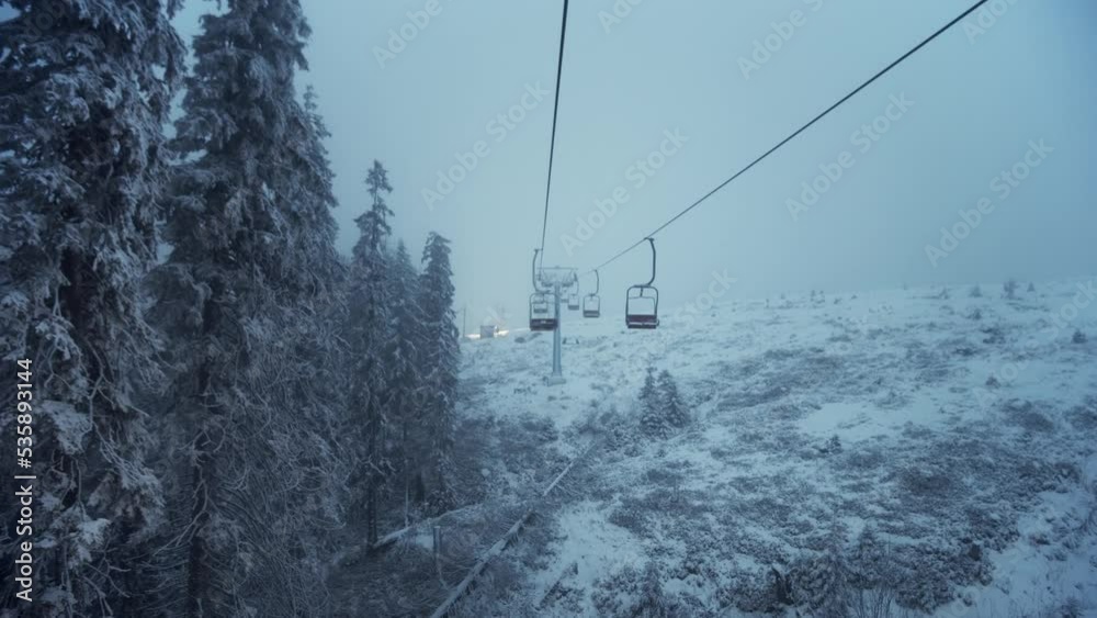 Drahobrat, Ukraine. Shot of people lifting on ski-lift with empty seats in mountains. Opening of ski resort season. Panoramic view. Ropeway cabines. Forest. Outdoors. Nature and sport Drahobrat, Ukraine. Shot of people lifting on ski-lift with empty seats in mountains. Opening of ski resort season. Panoramic view. Ropeway cabines. Forest. Outdoors. Nature and sport