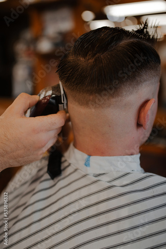 A haircut. Barber cuts a guy's hair in a barbershop close-up with a blurred background