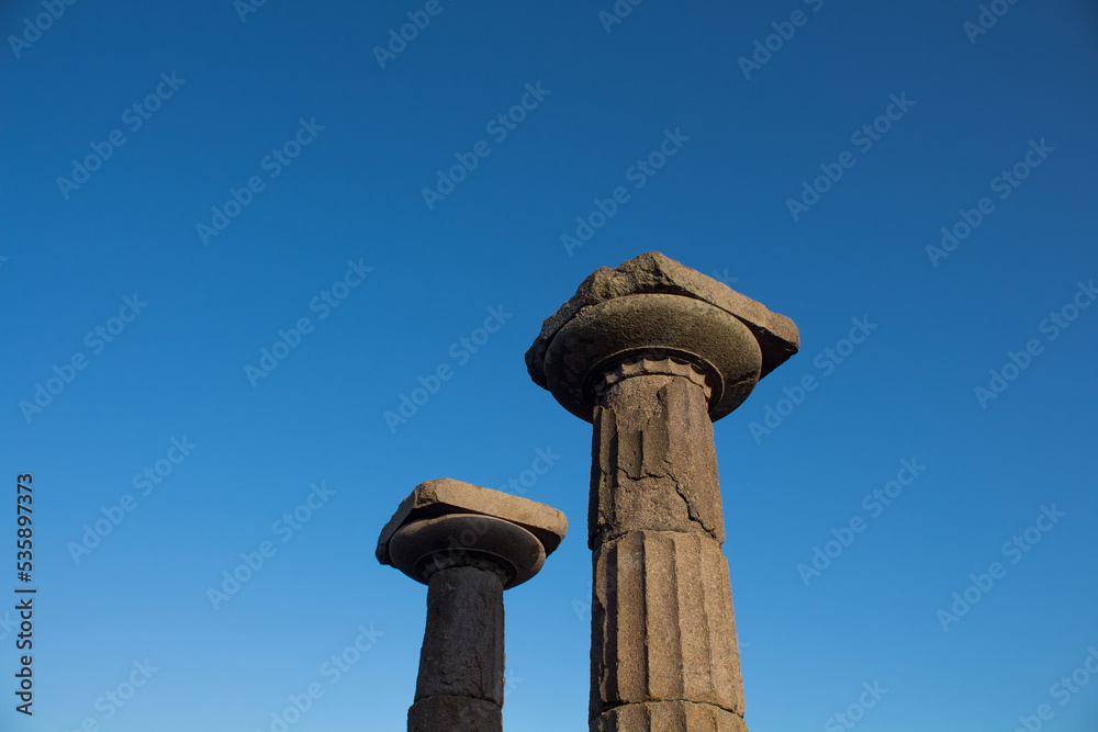 View of historical ruins with clear, blue sky background captured in the temple of Athena at the ancient city of Assos located in Behramkale, Turkey