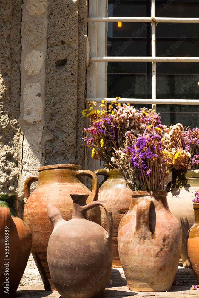 View of old, historical, traditional ceramic pottery with colorful flowers. Handmade amphora works captured in famous, touristic Aegean town called Alacati. It is a village of Cesme, Turkey.
