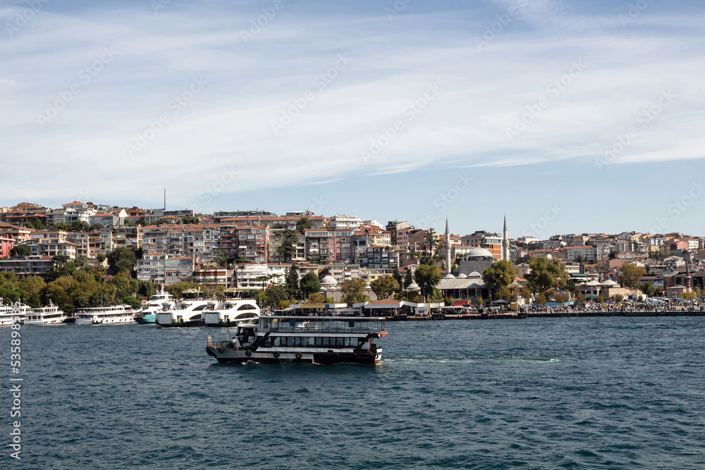 View of a tour boat on Bosphorus and Uskudar district on Asian side of Istanbul. It is a sunny summer day.