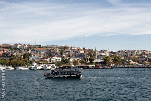 View of a tour boat on Bosphorus and Uskudar district on Asian side of Istanbul. It is a sunny summer day.