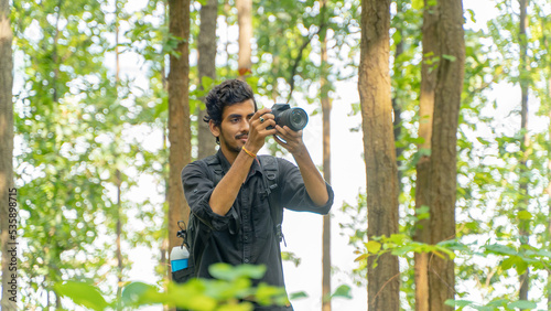 Photography Young photographer standing in the nature, taking picture with professional came