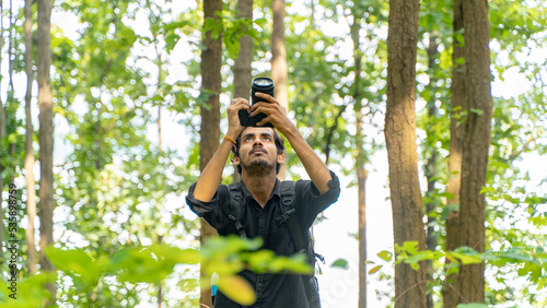Canvas Print Young photographer standing in the nature, taking picture with professional came