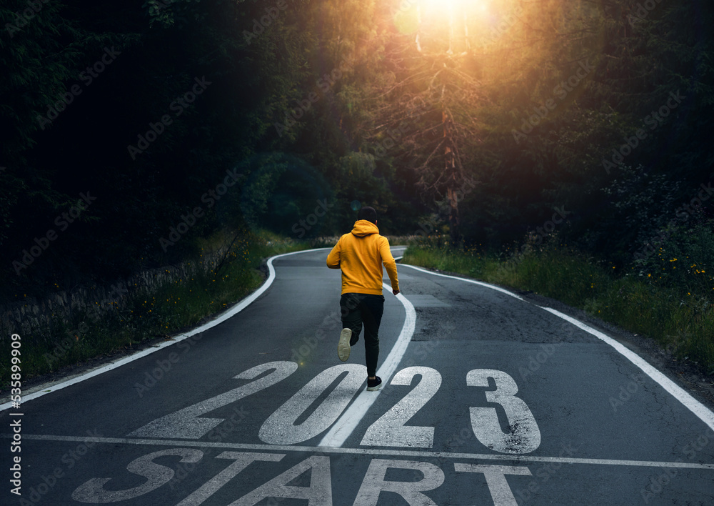 2023 with new ambitions, challenge, plans, goals and visions.  Man running on the mountain road towards new goals in 2023.  - obrazy, fototapety, plakaty 