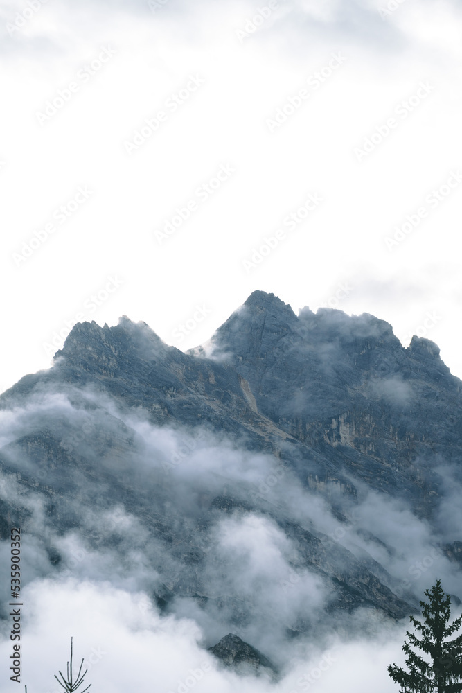 Amazing misty morning on the stunning Dolomite mountains in Italy. Pine forest with clouds and mist