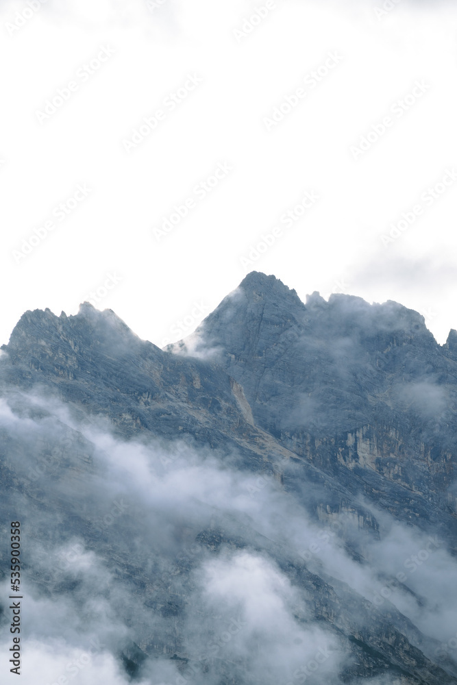 Amazing misty morning on the stunning Dolomite mountains in Italy. Pine forest with clouds and mist