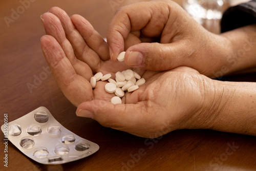 Hand holding medicine pills on wooden surface. Selective focus.