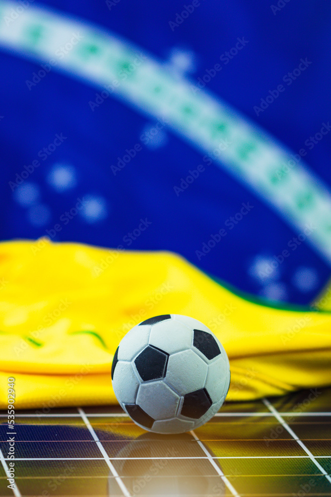 Naklejka premium Soccer Ball and Brazil Flag over Photovoltaic Solar Panel. World Cup and Technology Concept Image for Design.
