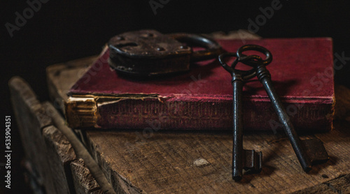 libro antiguo de tapa dura, candado y llaves antiguas sobre mesa de madera 