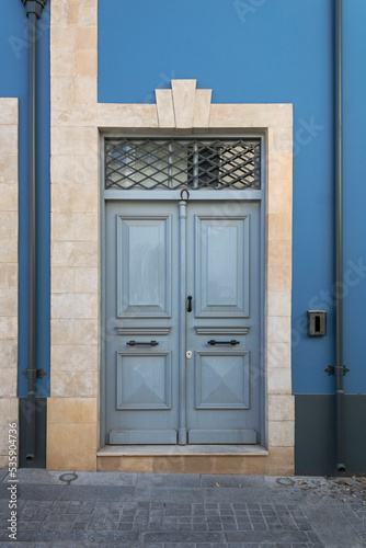 Blue stone wall with gray retro style wooden door in natural stone doorway