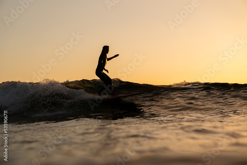 Canvas Print Surfista mujer en atardecer surf ola sobre tabla de surf cielo naranja