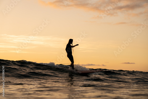 Photography Surfista mujer en atardecer surf ola sobre tabla de surf cielo naranja