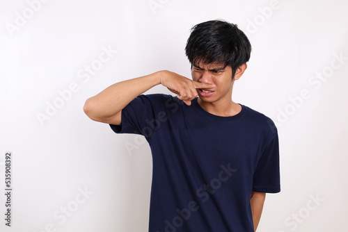 Asian young man standing while covering his nose. Bad smell concept. Isolated on white background