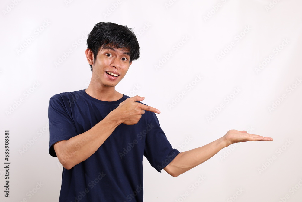 Happy asian young man standing while pointing