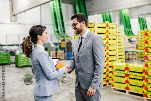 Two business people shaking hands in food factory.
