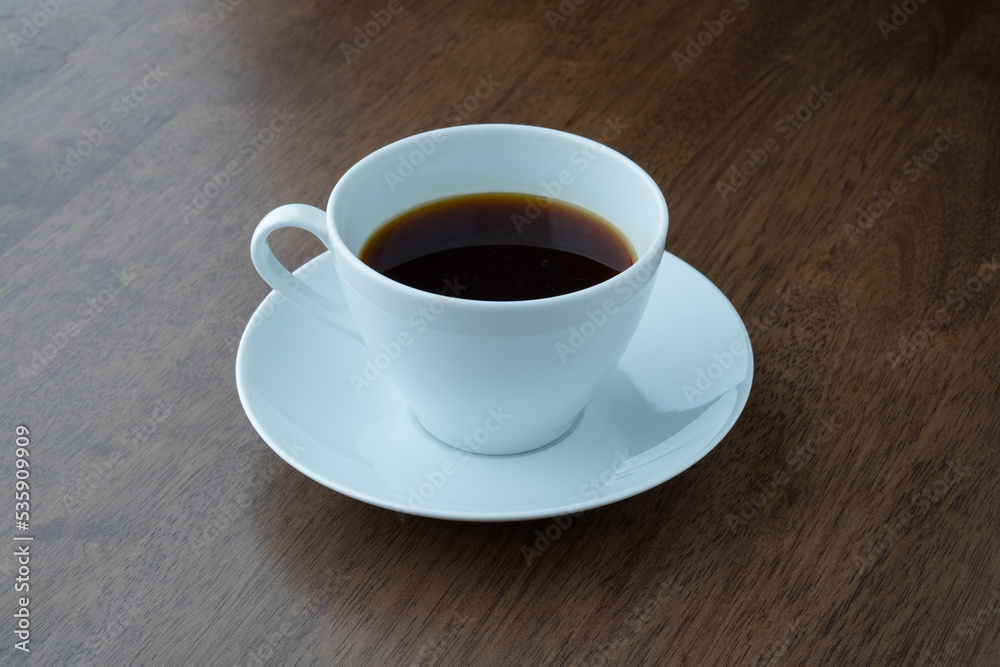cup of black coffee on a table with a wood texture