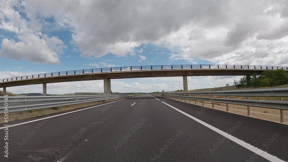 POV driving a car on empty highway road through the fields outside the city during sunny day. Two way asphalt road country views with low clouds at Spain. Traffic ways transportation concept. POV driving a car on empty highway road through the fields outside the city during sunny day. Two way asphalt road country views with low clouds at Spain. Traffic ways transportation concept.