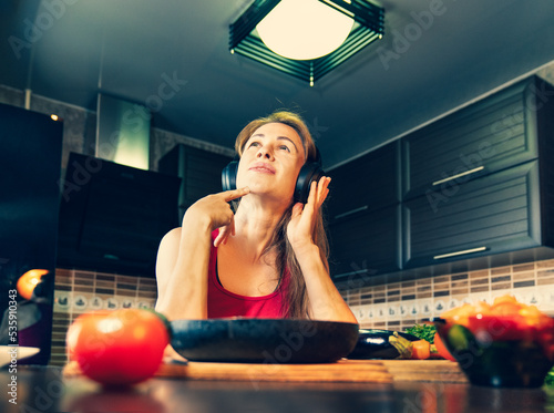 girl in headphones sitting at the table in the kitchen