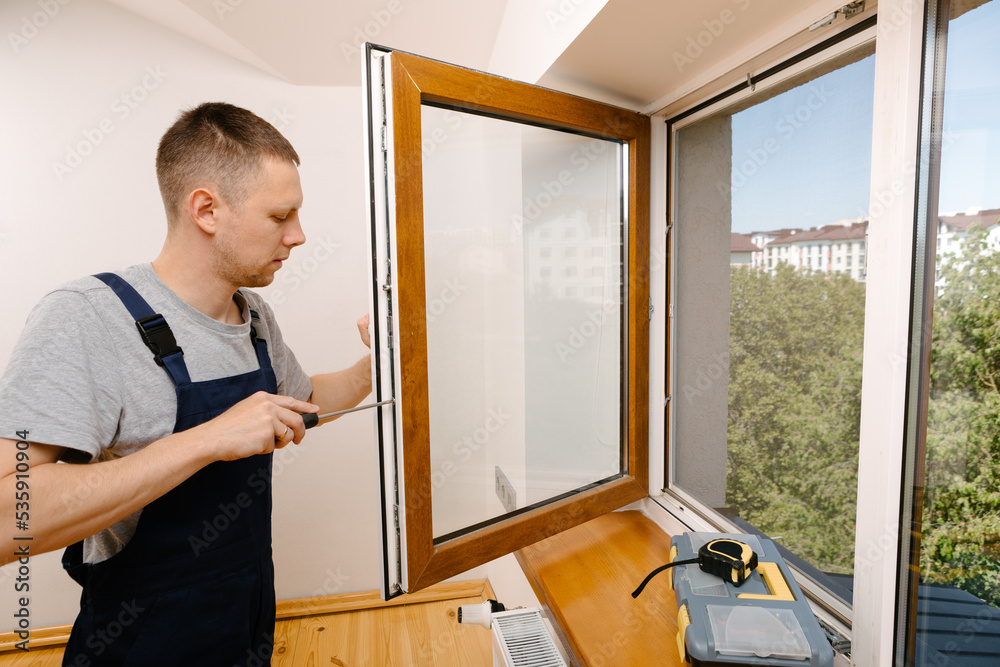 Fototapeta premium The worker installing and checking window in the house