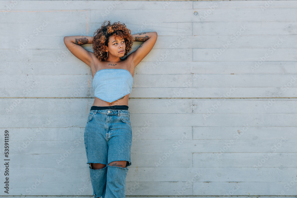 relaxed latin girl leaning on street wall outdoors