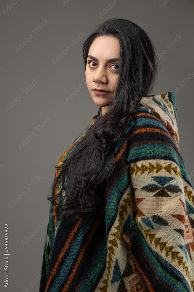 natural beauty and fashion with poncho, colorful and warm clothes wearing by young latin woman with black eyes and hair in studio natural beauty and fashion with poncho, colorful and warm clothes wearing by young latin woman with black eyes and hair in studio