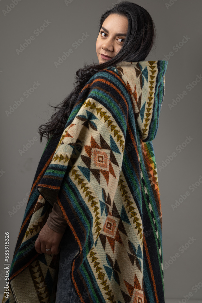 modeling a colorful and warm poncho wearing by a young latin woman with black eyes and hair in studio, traditional fashion and beauty modeling a colorful and warm poncho wearing by a young latin woman with black eyes and hair in studio, traditional fashion and beauty