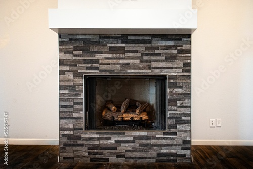 Gray fireplace with unlit firewood inside on a white background of living  room wall photo