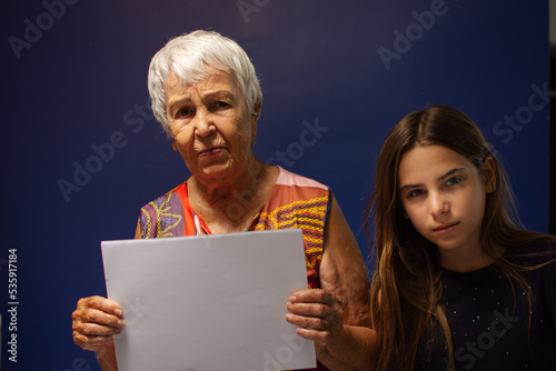 Aó com a neta e segurando uma folha de papel em branco para reclame photo